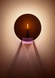 Spegla Wall Edition round mirror with a pink crystal glass candle holder glowing with a lit candle by Jochen Lavéno Mangelsdorff