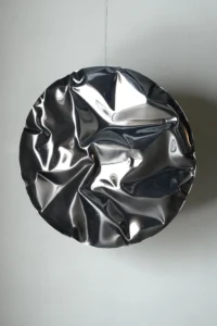 Ramé round wall sculpture in mirror-polished stainless steel with deep folds that reflect the room, by Nitush and Aroosh